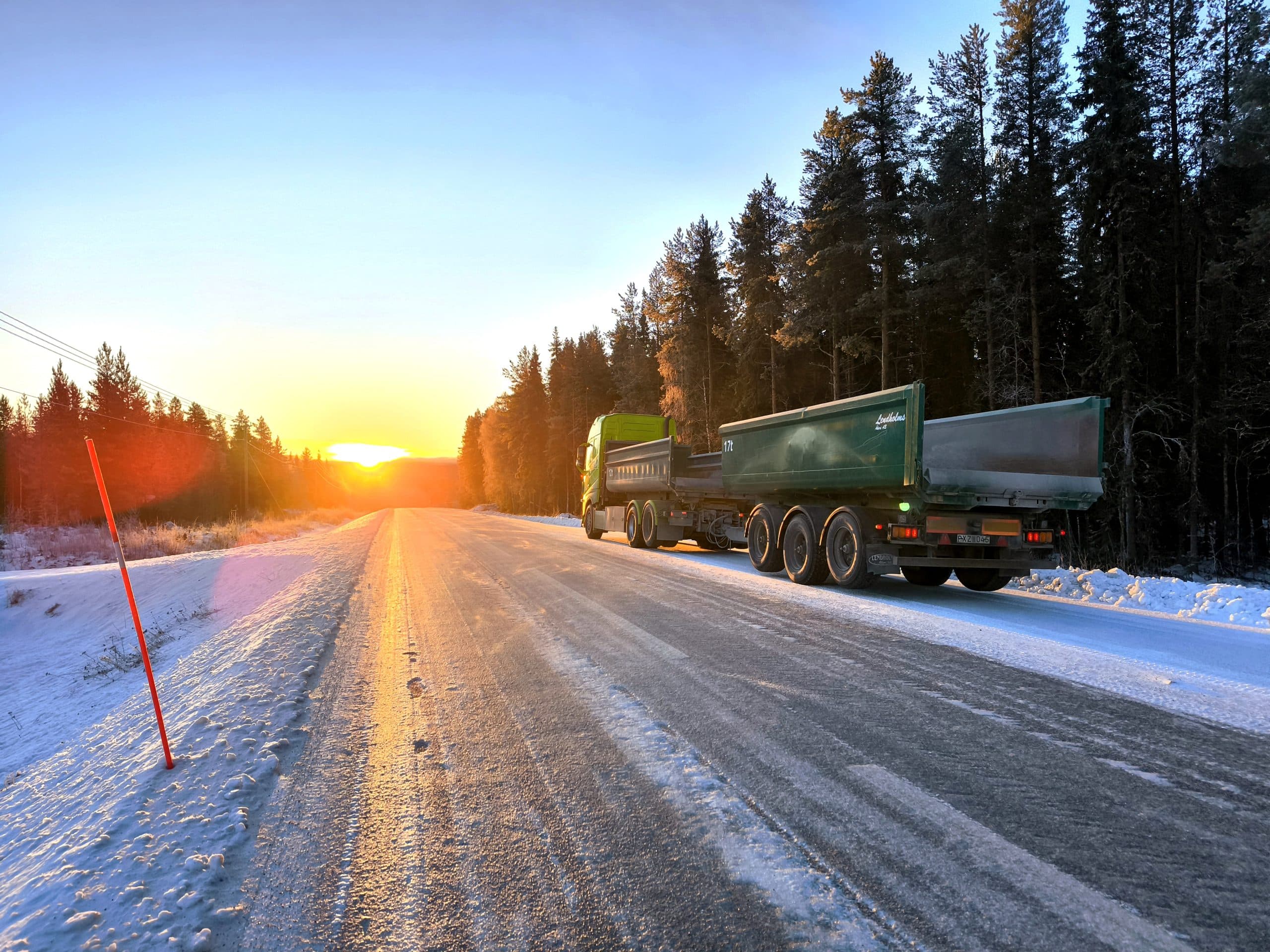 Lastbil på vinterväg i solnedgång